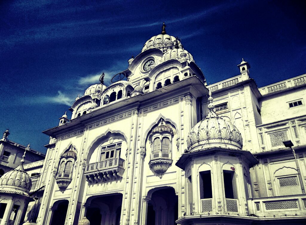 A stunning white Sikh temple with intricate details against a clear blue sky.